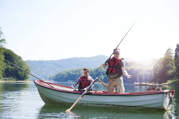 Senior man met zoon vissen in lake  - Foto, afbeelding