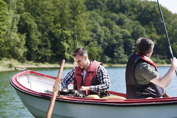 息子と父親のボートで魚のための準備を行う - 写真・画像