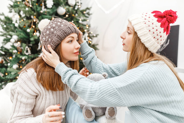 Женщины-друзья во время Рождественской вечеринки на вечеринке в вязаных шляпах, концепция дружбы и отношений в современном обществе
 - Фото, изображение