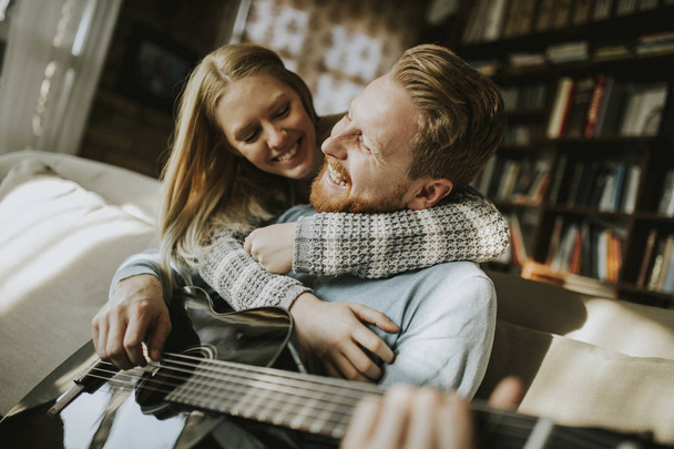 Hombre tocando la guitarra acústica para su joven hermosa mujer
 - Foto, imagen