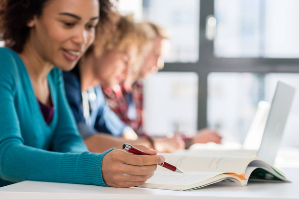 Close-up de estudantes segurando canetas perto de livros enquanto estudam em sala de aula
 - Foto, Imagem