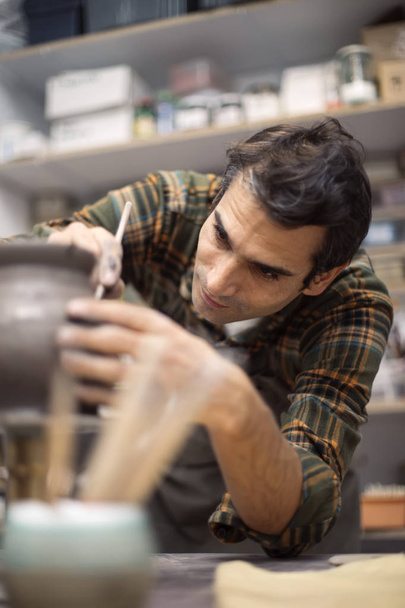 Młody mężczyzna zdobienia ceramiki w pracowni - Zdjęcie, obraz