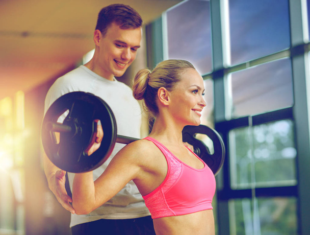 smiling man and woman with barbell in gym - Fotografie, Obrázek
