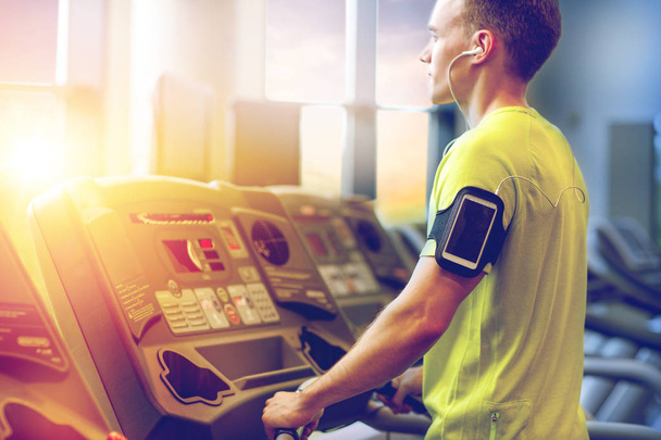 man with smartphone exercising on treadmill in gym - Photo, Image
