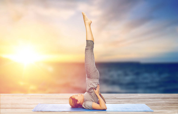 woman doing yoga in shoulderstand pose on mat - Фото, зображення