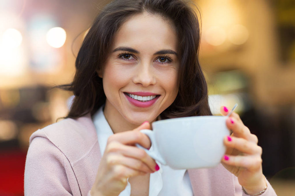 Jonge vrouw die koffie drinkt in café - Foto, afbeelding