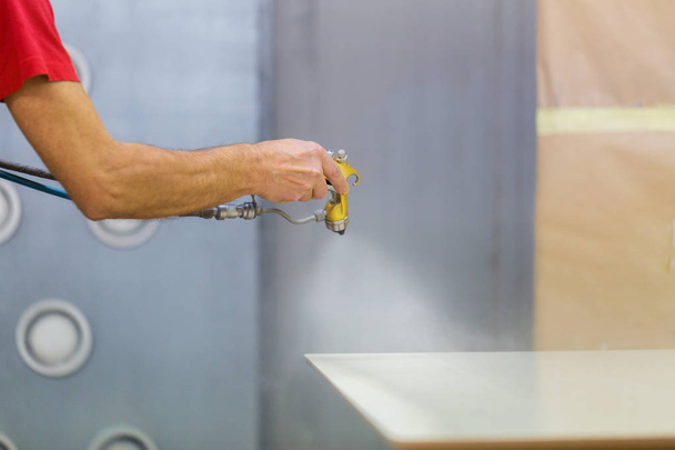 worker hand sprays urethane finish to board - Фото, зображення