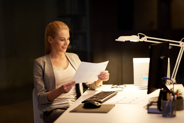 businesswoman with papers working at night office - Photo, image