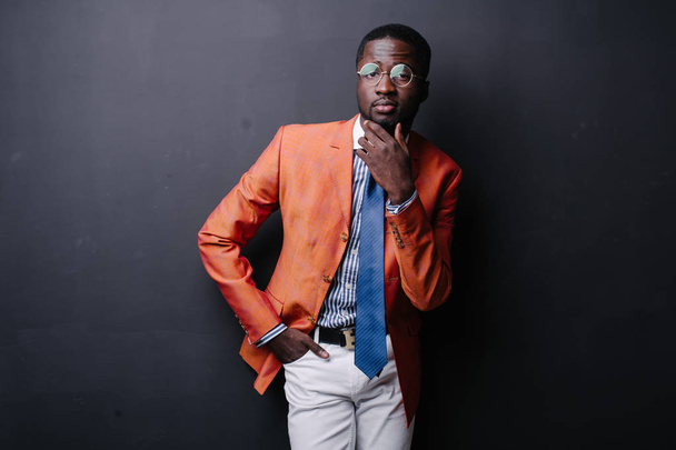 Selbstbewusster junger Afrikaner posiert in orangefarbener Jacke  - Foto, Bild