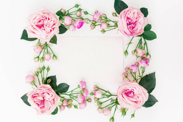 Floral σύνθεση με ροζ τριαντάφυλλα, κλαδιά και φύλλα σε άσπρο φόντο. Επίπεδη lay, κορυφαία προβολή. - Φωτογραφία, εικόνα