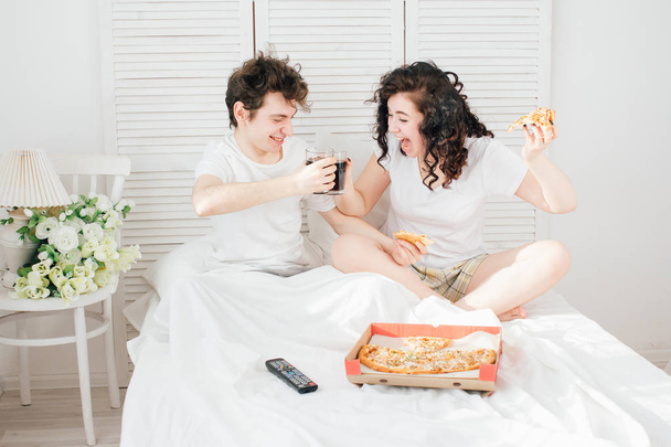Couple watching TV in bed and eating pizza - Foto, imagen