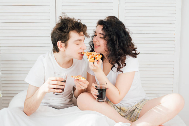 Couple watching TV in bed and eating pizza - Zdjęcie, obraz