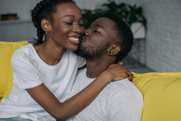 beautiful happy young african american couple hugging and kissing at home - Φωτογραφία, εικόνα
