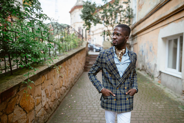 Confident young African man  in a stylish suit  on city street - 写真・画像