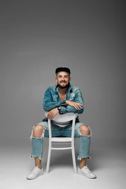 man in a cap and jeans suit on a gray background in the studio - Fotó, kép