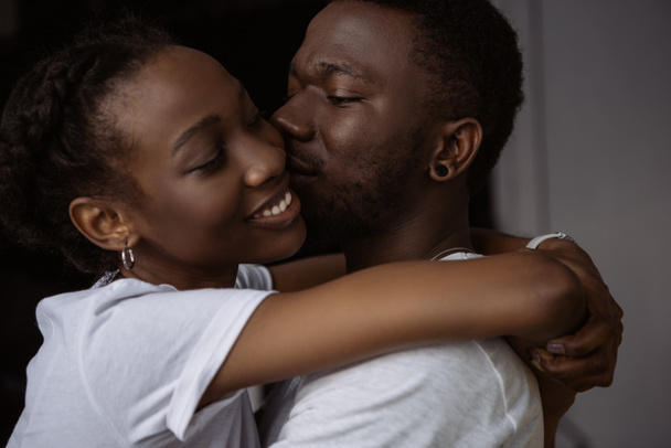 όμορφο ευτυχισμένο ζευγάρι Αφρικανικός Αμερικανός αγκάλιασμα και το φίλημα στο σπίτι - Φωτογραφία, εικόνα