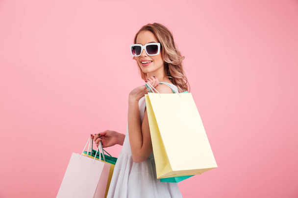 Happy young woman wearing sunglasses holding shopping bags. - Foto, Imagen
