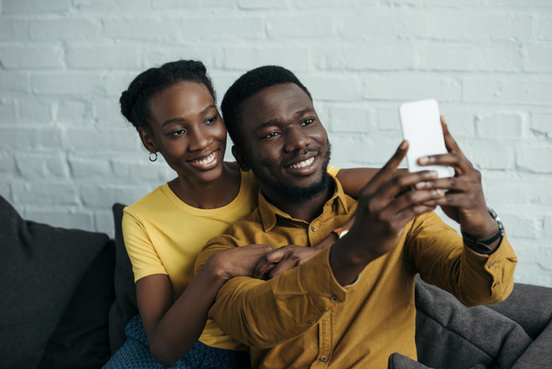 mooie gelukkige jonge Afro-Amerikaanse paar nemen selfie met smartphone thuis - Foto, afbeelding