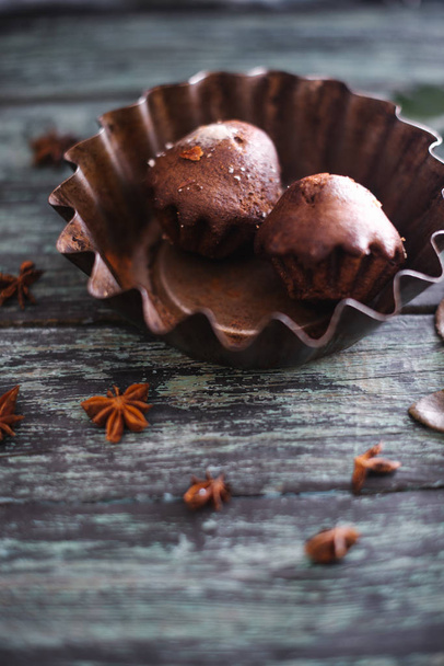 Cupcakes on a dark wooden background with rose branches. - Фото, зображення