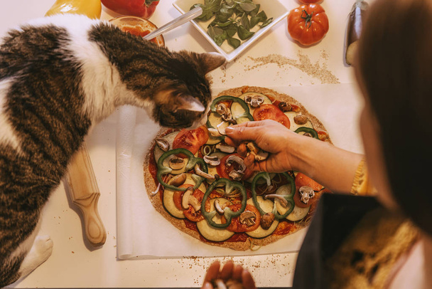 Woman preparing delicious pizza with her sweet cat. - Foto, Imagem