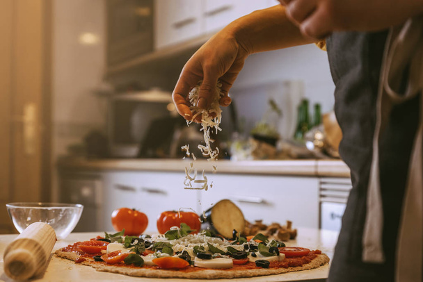 Woman adding healthy ingredients to pizza. - Фото, изображение