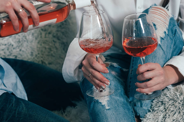 A man in jeans fills glasses with rose wine - 写真・画像