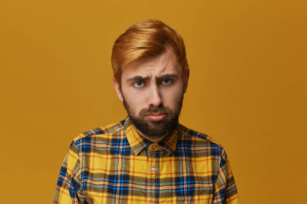Curvas masculinas frustradas estresadas labio inferior, lleva camisa amarilla y se ve disgustado en la cámara. Fondo amarillo. Depresión e infelicidad
 - Foto, imagen