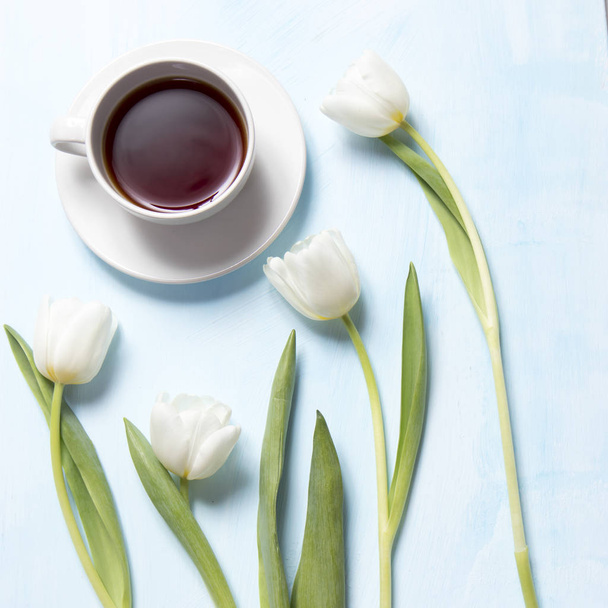 white tulips and tea in the mug on blue wooden background as a card - Foto, Imagen
