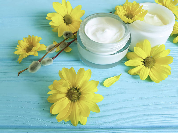 sauce, crema cosmética flores amarillas azul madera primavera fondo
 - Foto, Imagen