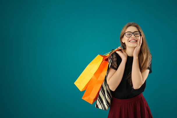Beautiful young woman with shopping bags on color background - Foto, immagini