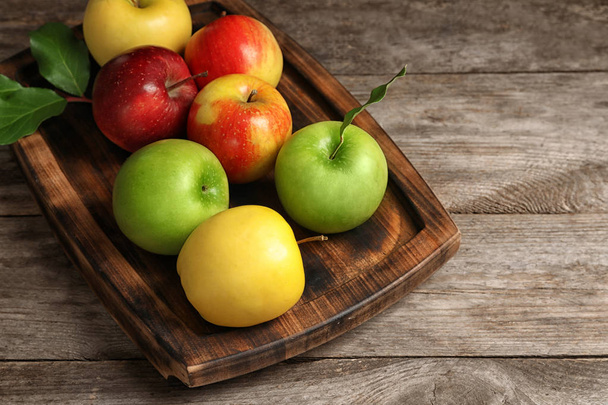 Tray with ripe juicy apples on wooden table - Фото, зображення