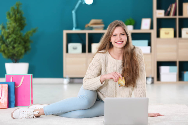 Young woman shopping online with credit card and laptop on floor - Foto, Bild