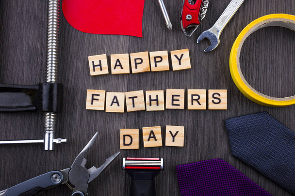 Frohe Vatertagsbotschaft auf hölzernem Hintergrund mit Rahmen aus Werkzeugen und Krawatten. - Foto, Bild