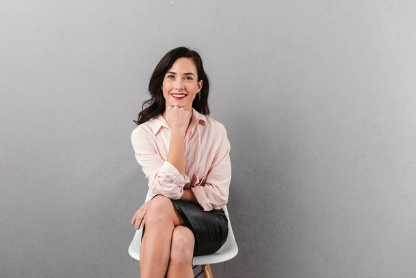 Portrait of a smiling businesswoman sitting in a chair - Foto, Imagem