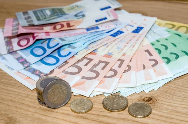 Euro banknotes and euro coins on wooden table - Фото, изображение