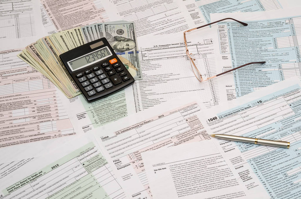 Formulario de impuestos 1040 con calculadora, bolígrafo y billetes de dólar
 - Foto, Imagen