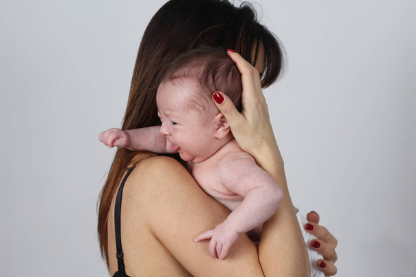 giovane madre che tiene il suo bambino piangente figlia in studio
 - Foto, immagini