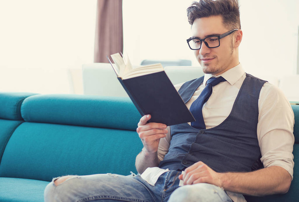 Content man reading book on couch - Foto, Imagen