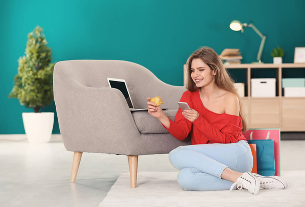 Young woman shopping online with credit card and mobile phone at home - Photo, Image