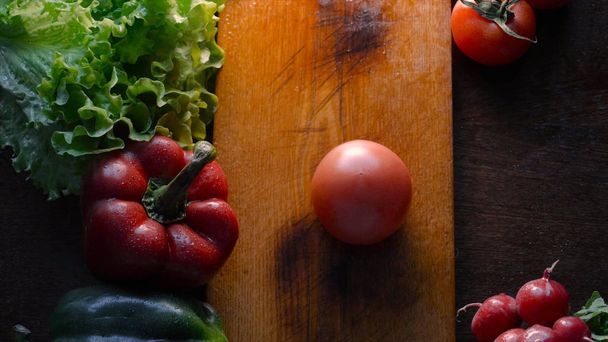 Keukentafel met groenten, tomaat, rode peper, gember, groene salade, champignons en mes. - Foto, afbeelding