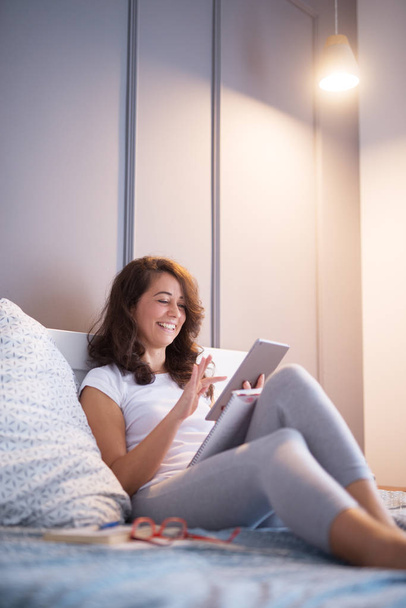 mulher bonita feliz sentado na cama e usando tablet pc em casa
 - Foto, Imagem