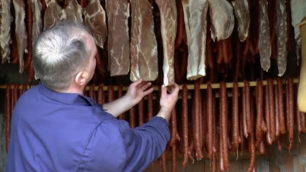 Arbeiter kontrolliert geräucherte Trockenwurst und geräuchertes Fleisch. - Filmmaterial, Video