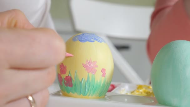 Mother and daughter draw Easter eggs with colored paints - Felvétel, videó