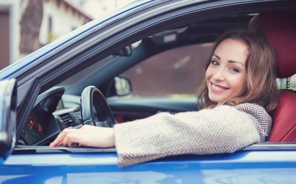 Pretty girl driving car smiling at camera - Zdjęcie, obraz