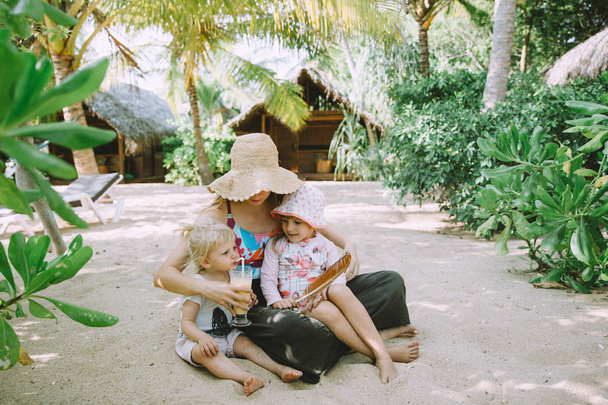 mladá matka s roztomilé malé dcery relaxační v tropické pláže - Fotografie, Obrázek