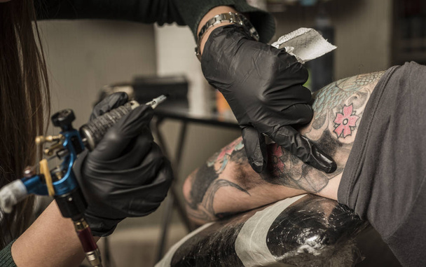 татуировщик делает фотографию профессионального мастера в черных перчатках - Фото, изображение