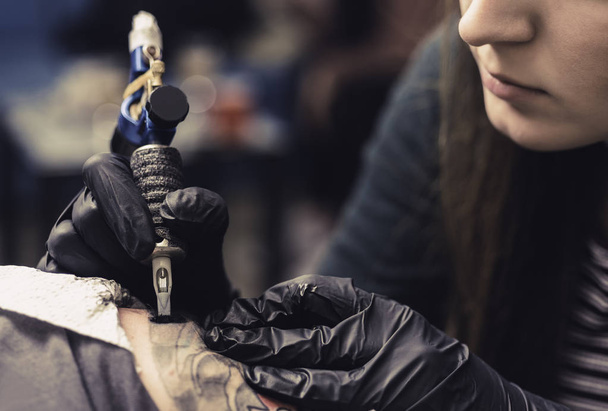 καλλιτέχνης τατουάζ συνεργάζεται με έναν επαγγελματία πλοίαρχο σε ένα εργαστήριο. - Φωτογραφία, εικόνα