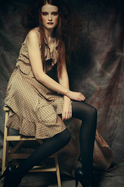young fashion model with creative make up sitting on a stool in  - Photo, image