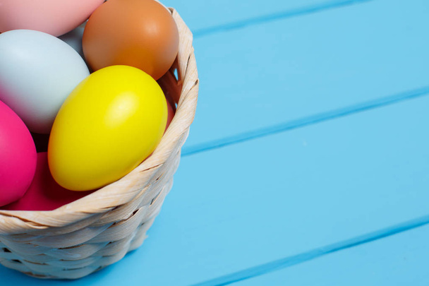 Пасхальные яйца в корзине на синем деревянном фоне
 - Фото, изображение