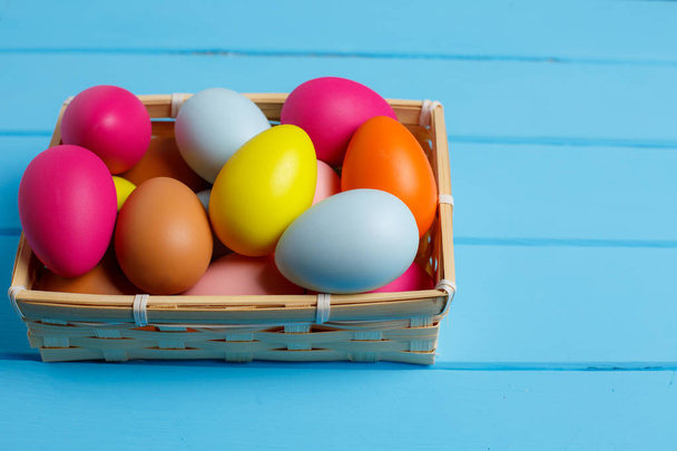 Пасхальные яйца в корзине на синем деревянном фоне
 - Фото, изображение